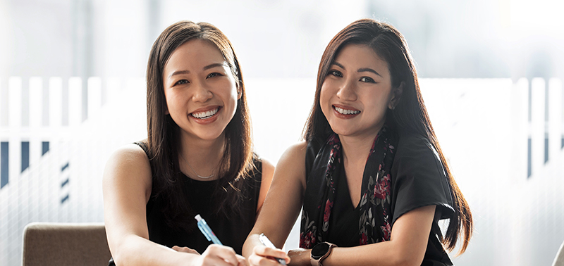 Two economists smiling and posing together in an office setting.